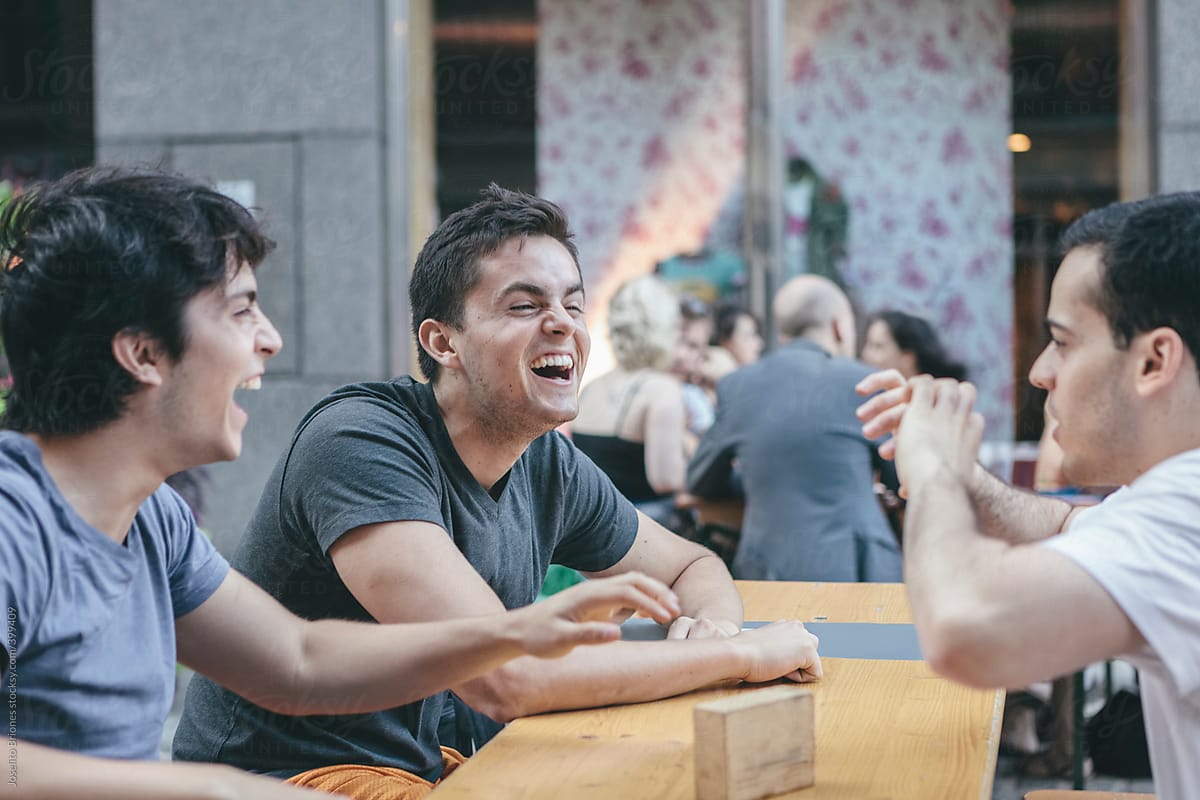 Group of Young Hispanic-Latino Men Having Fun Hanging Out at Outdoor Cafe in New York\'s Financial District