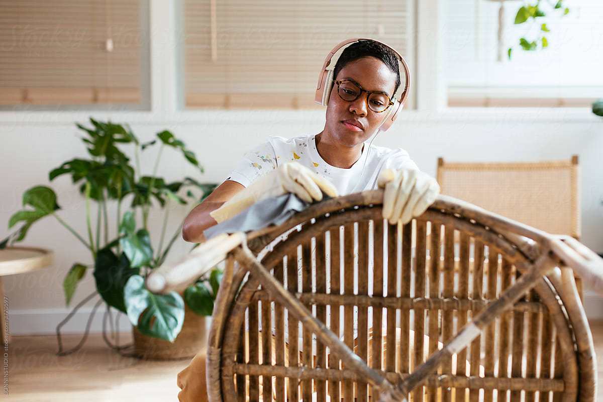 Black woman listening to music and wiping bamboo table