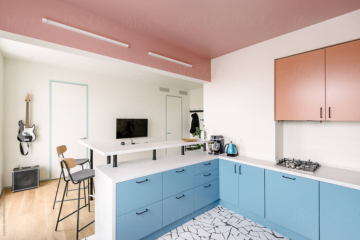 Kitchen and living room of a colourful flat with a guitar hanging on the wall.