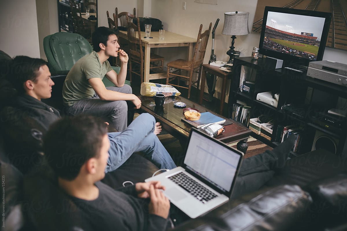 Group of Young Male University Students - Roommates Watching TV and Laptop on Couch