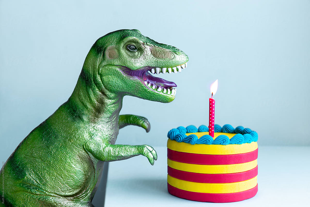 Happy dinosaur celebrating with colorful birthday cake
