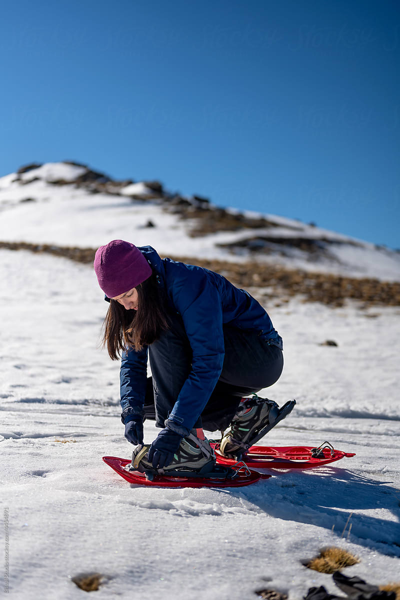 Climber putting on snowshoes in snowy highlands