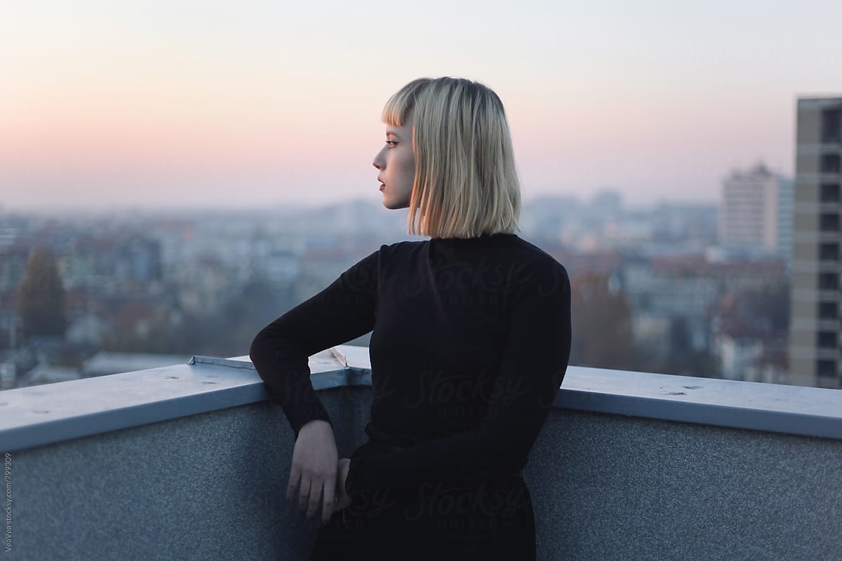 Portrait of a stylish young woman on the roof of the building during sunset