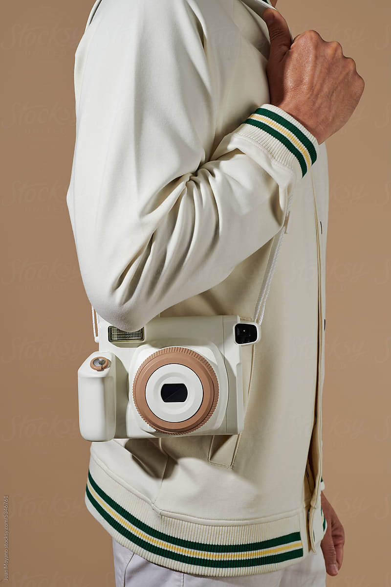 man carrying an off-white instant camera