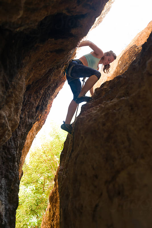 Young woman rock climbing a narrow crack