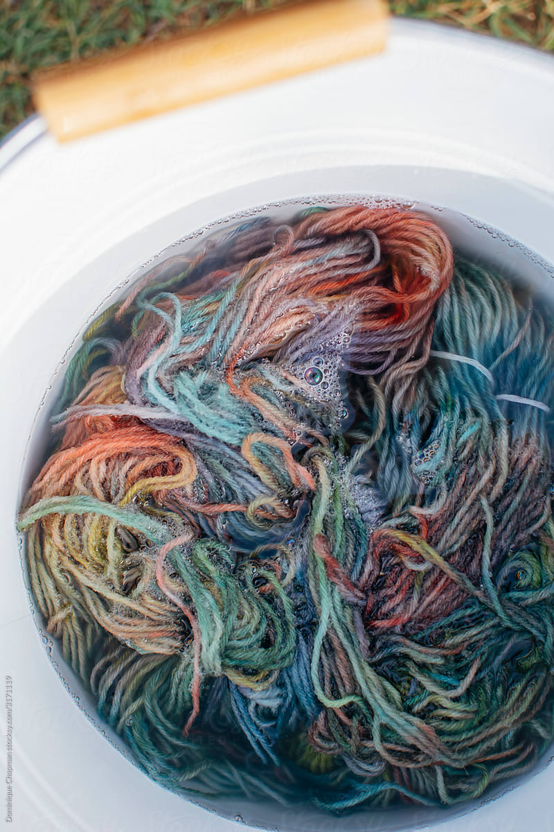 Colourful yarn being washed in a bucket