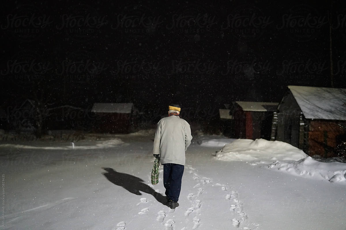 elderly gray-haired man walks in a dark winter night