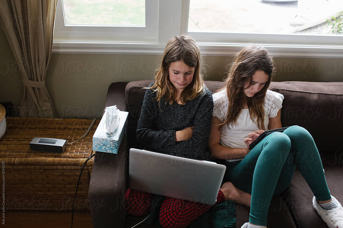 Kids using screens on couch at home. Technology tablets and computers at home.