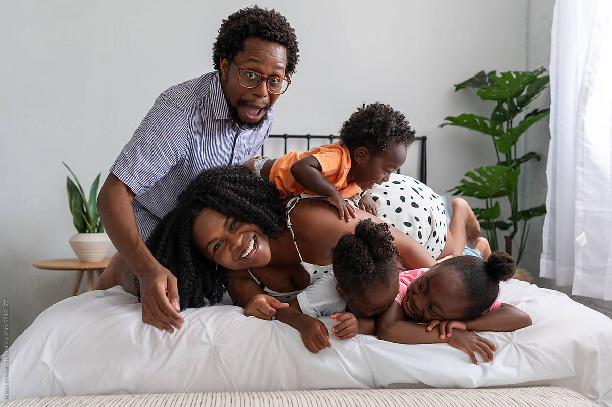 Candid family on a bed all climbing on each other and acting silly