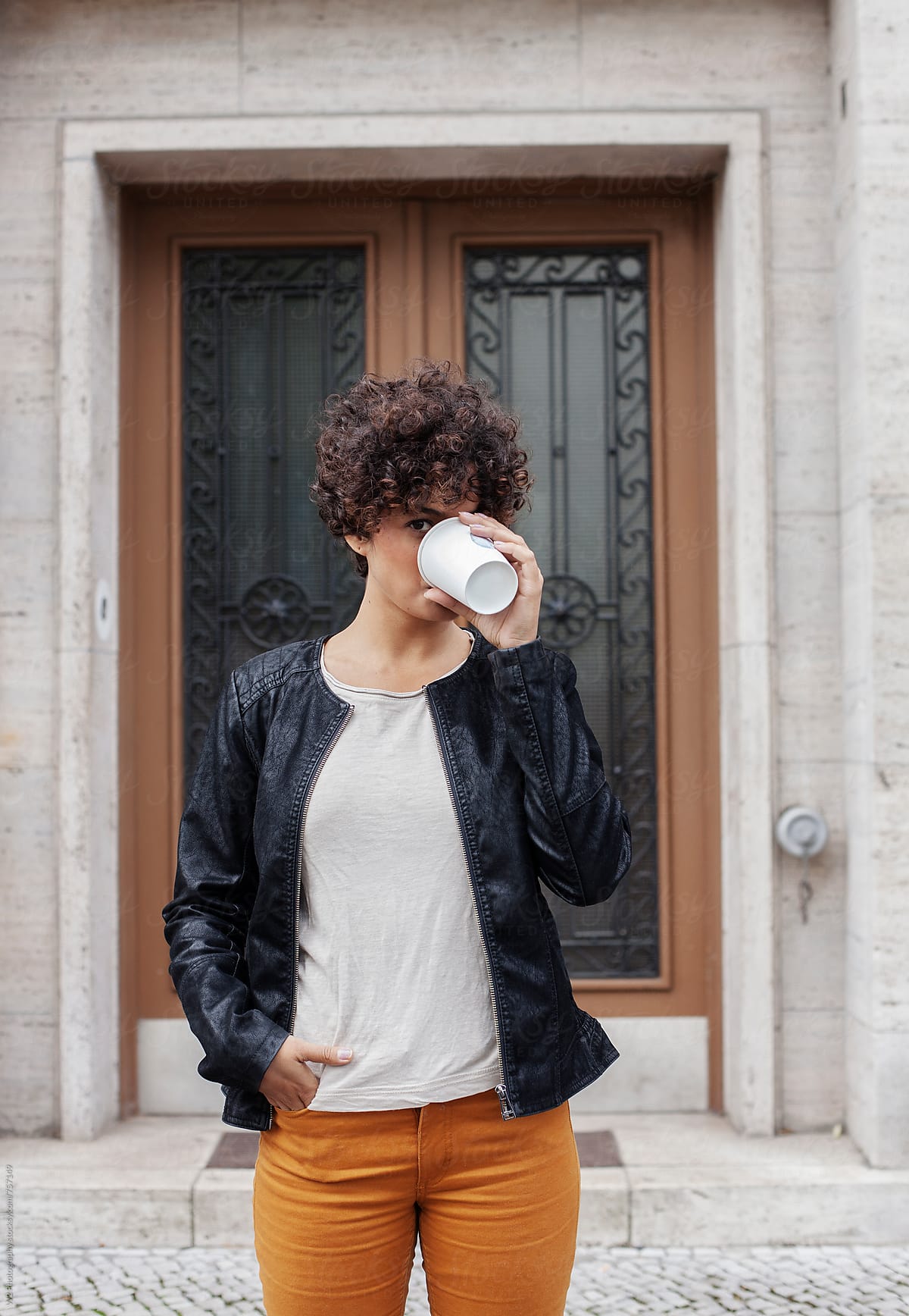 Portrait of young woman drinking coffee outdoors.