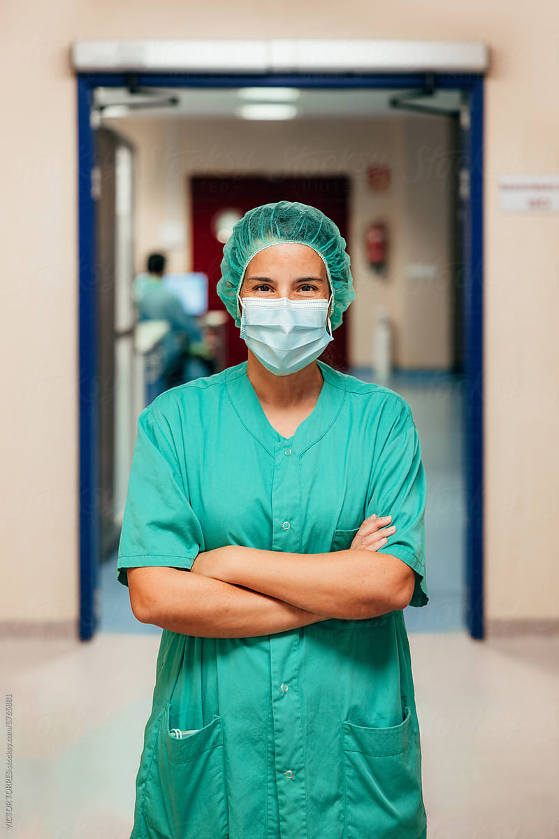 Confident surgeon posing in medical scrubs in a hospital corridor