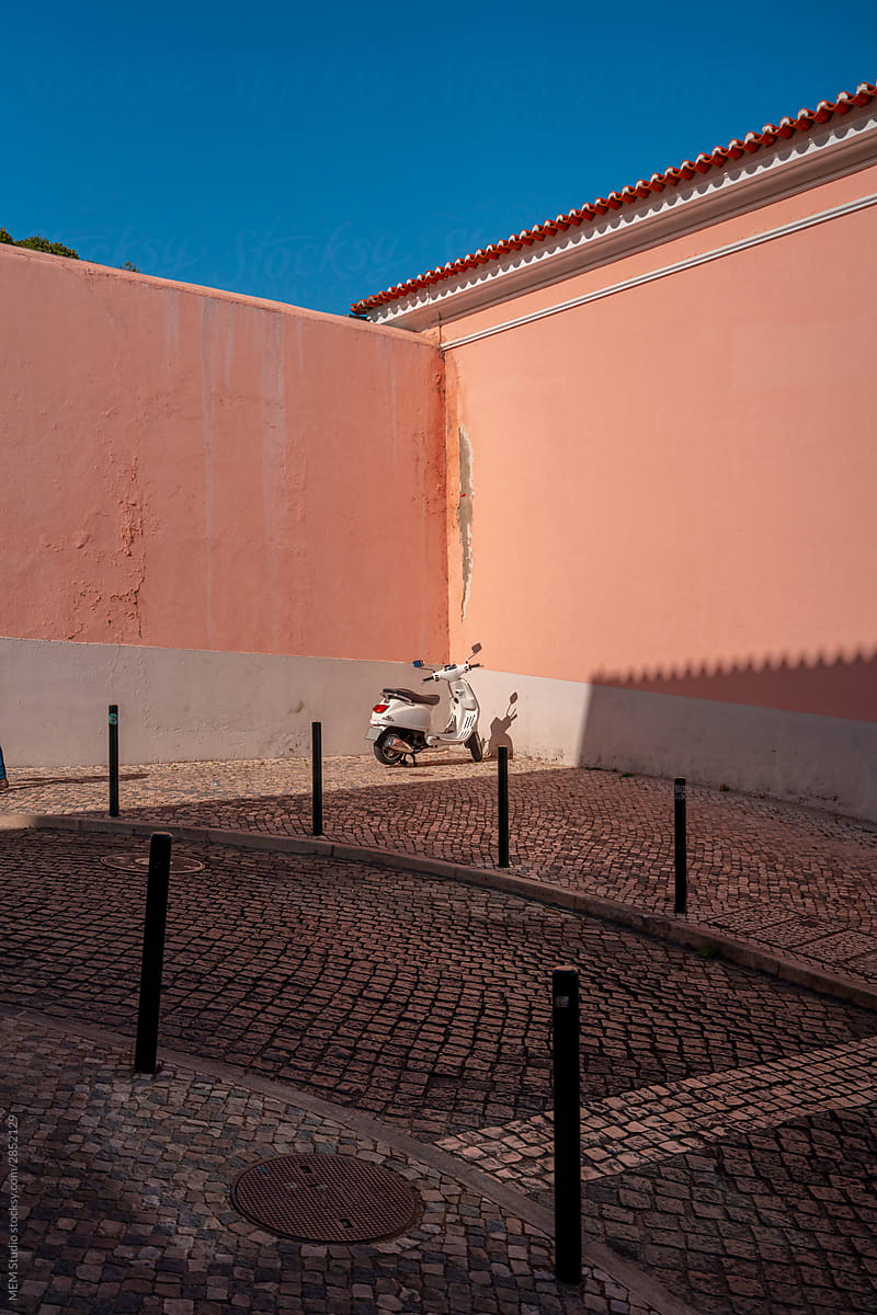 Moped parked agains pink wall