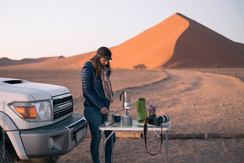 Woman on a roadtrip in the desert stopping to make coffee by the side of the road at dawn