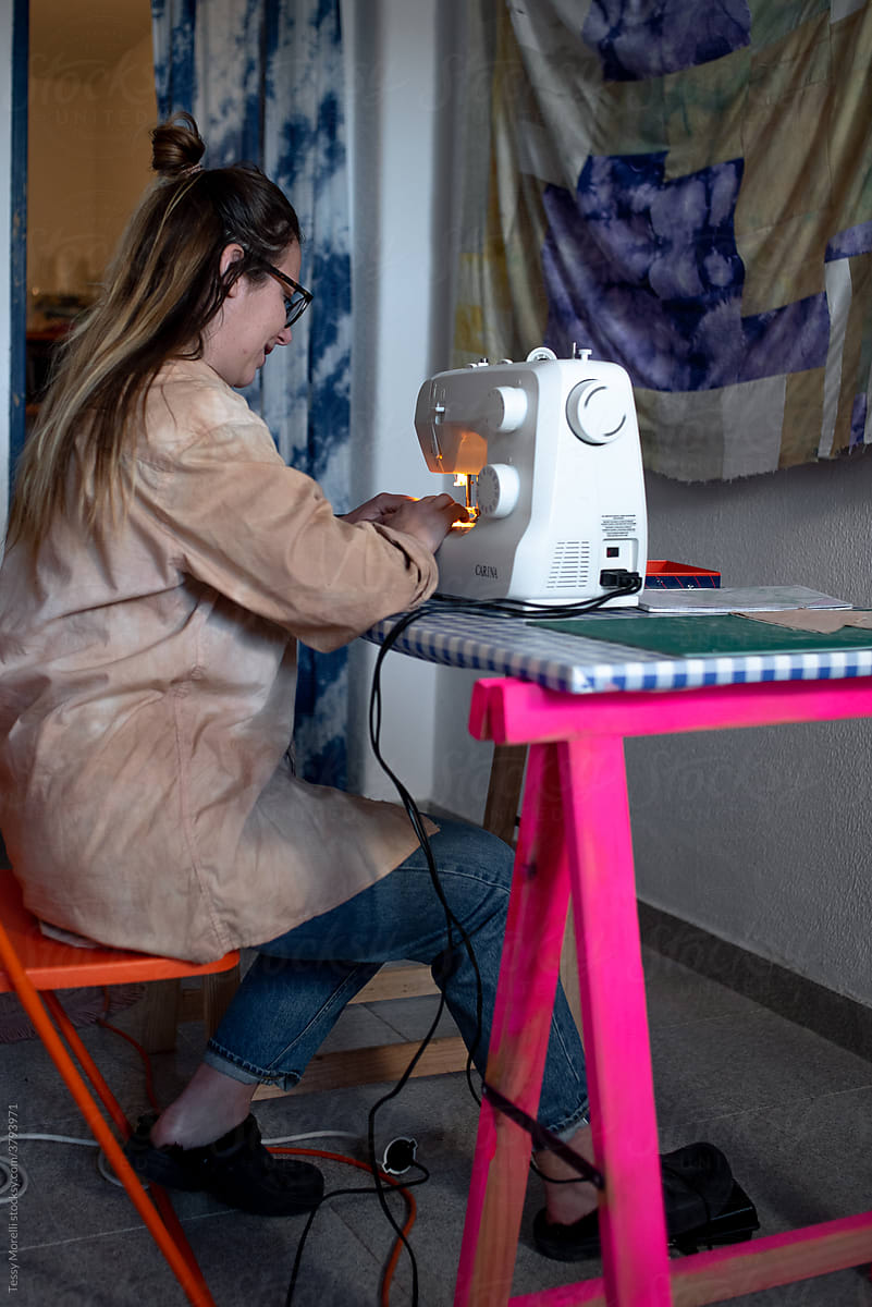 Woman at the home studio sewing on the desk