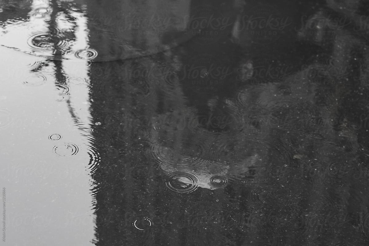 Puddle reflection of anonymous people with umbrellas
