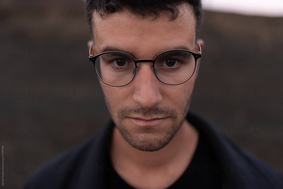 Close-up portrait of a man wearing glasses with a serious expression