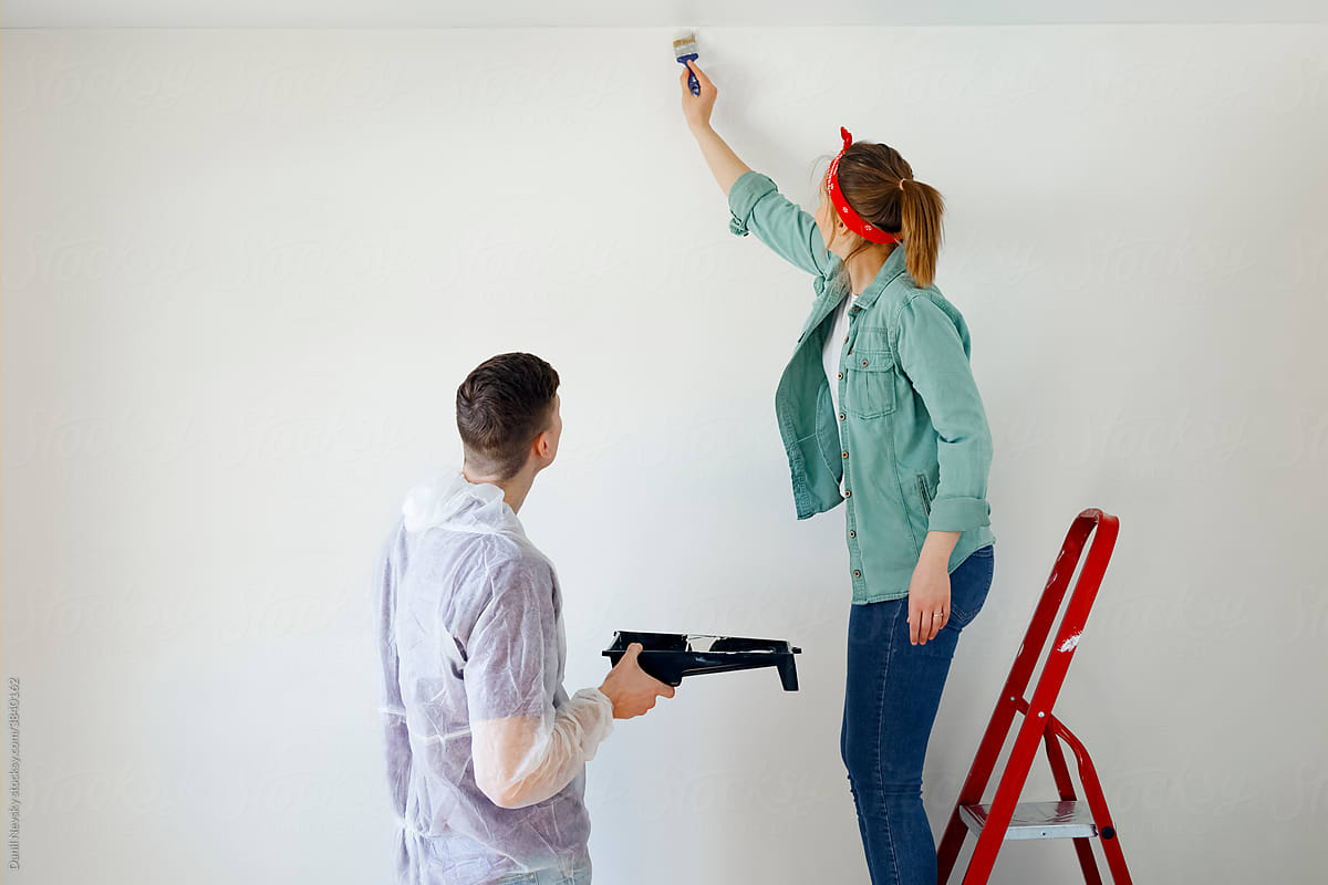 Married couple painting white wall at home