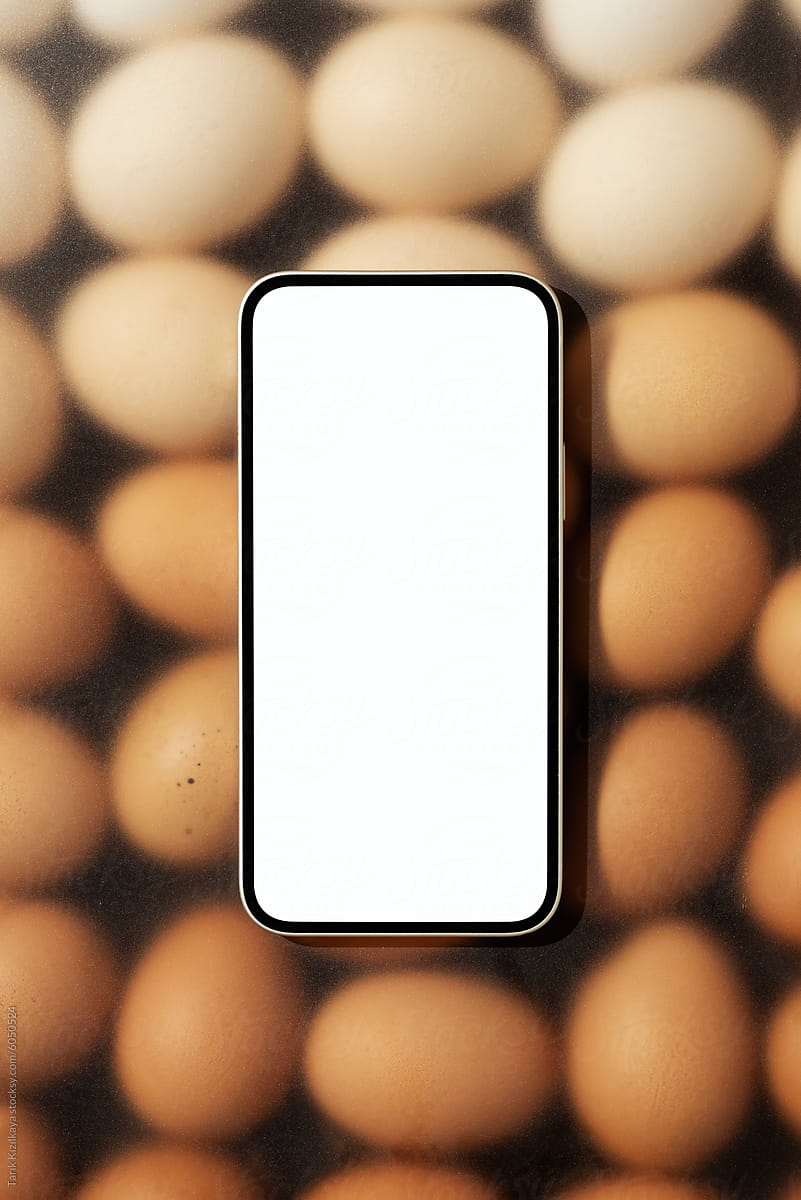 Blank screen smartphone on brown eggs under frosted glass