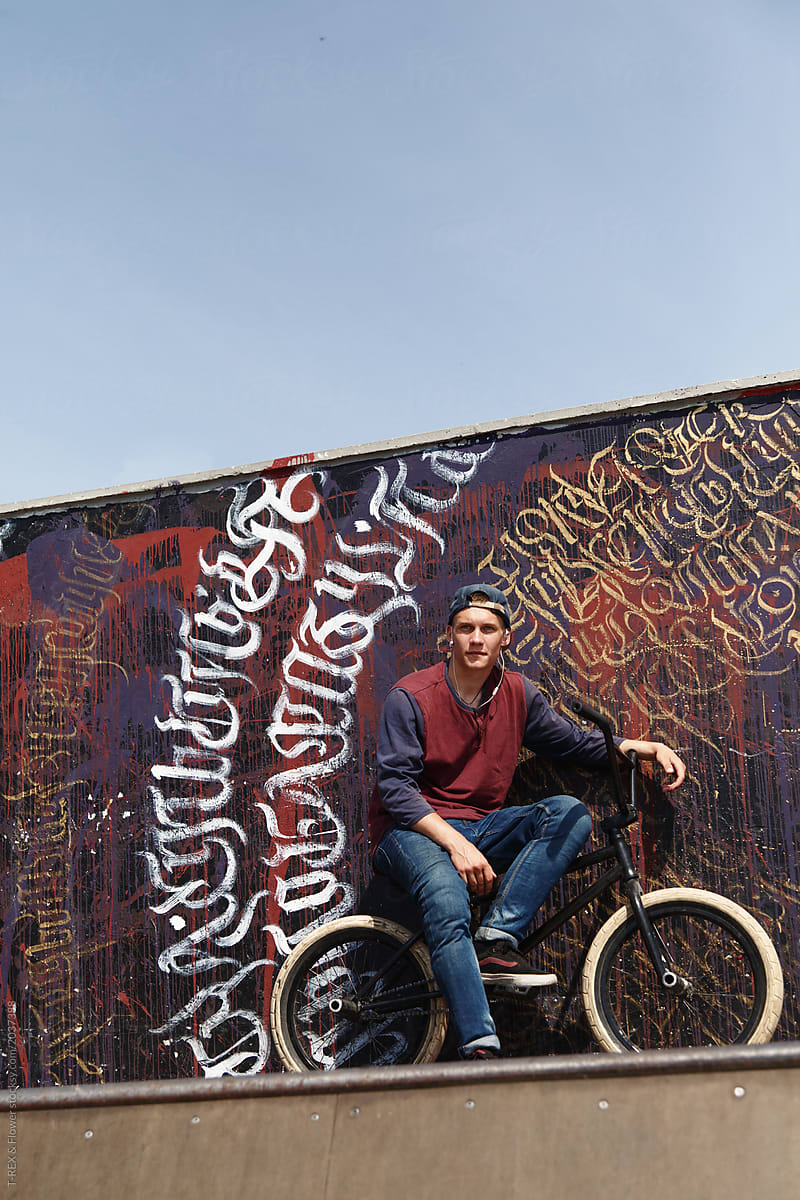 Young biker sitting at graffiti wall
