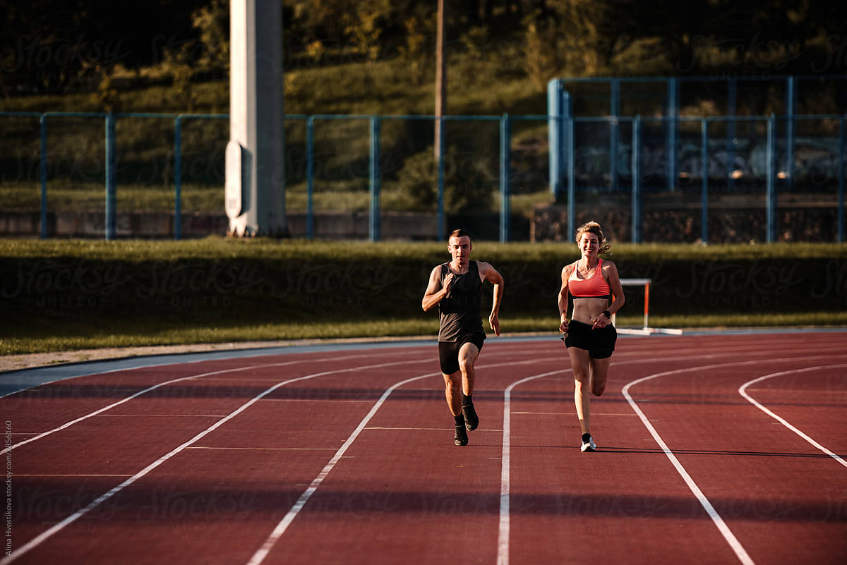 Sports man and woman running in stadium