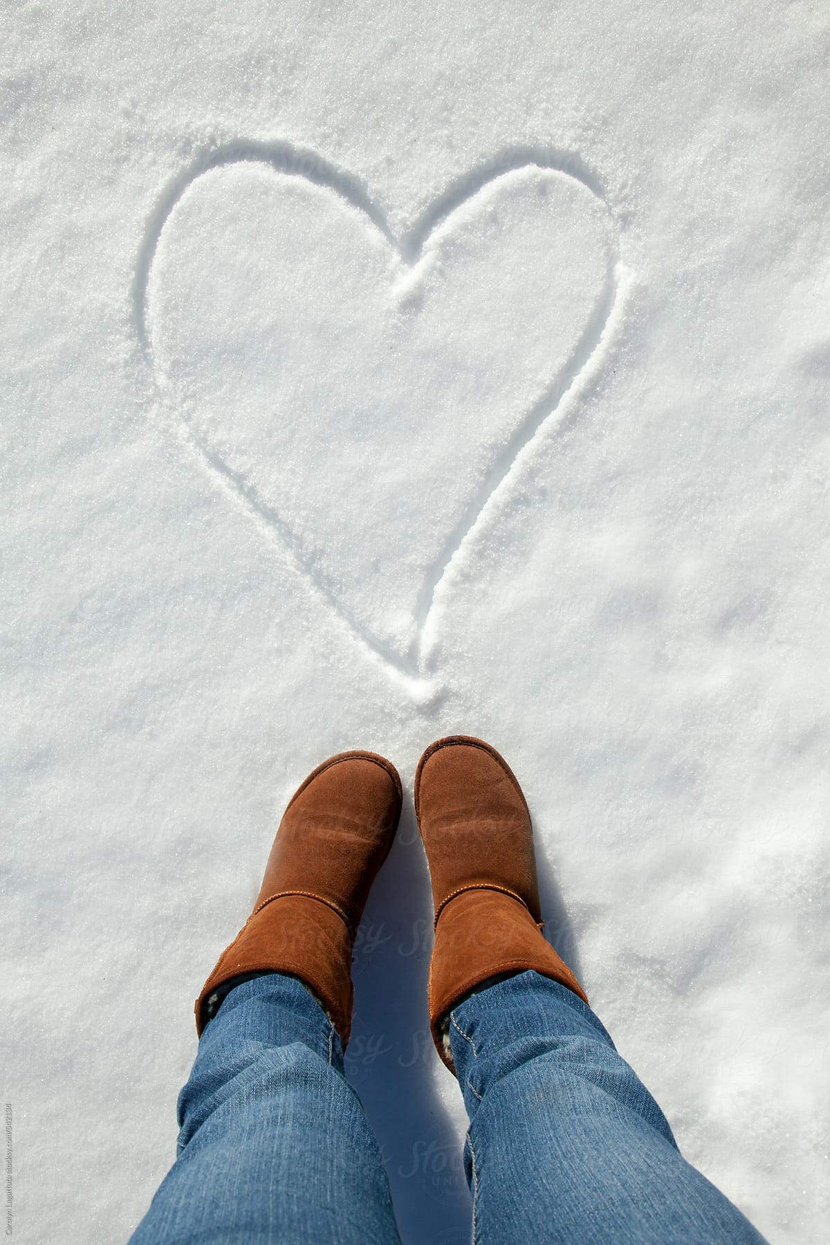 A person standing above a heart drawn in the snow