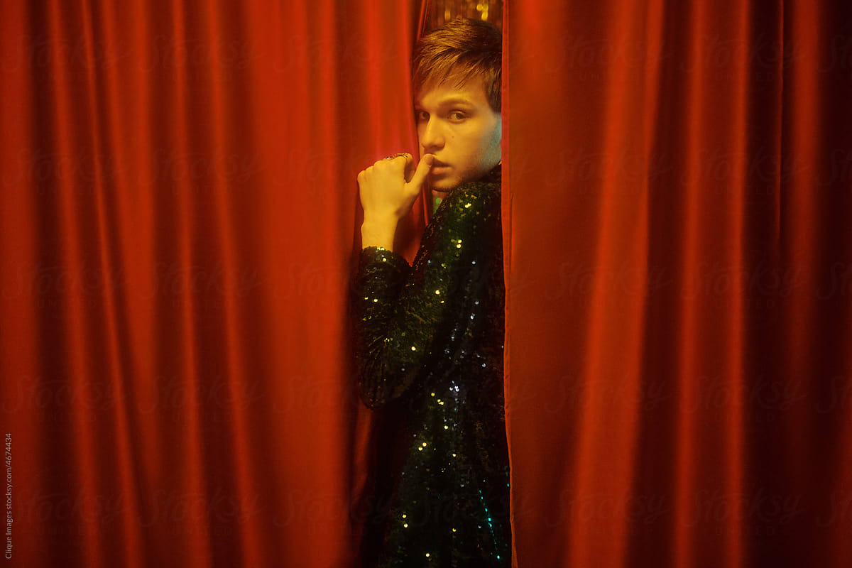 Young Queer Man Between Red Curtains