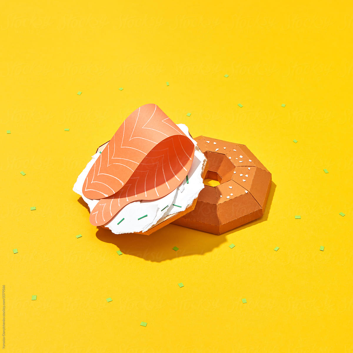 Handmade crafting bun with pieces of paper cheese and a piece of salmon on a yellow background with copy space. Snack. Flat lay