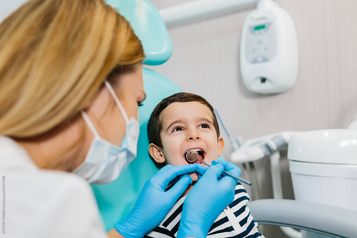 Dentist examining teeth of boy at workplace