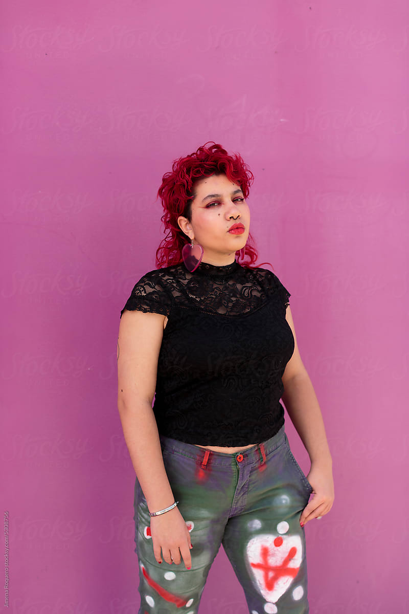 Non-binary person over pink background looking at camera