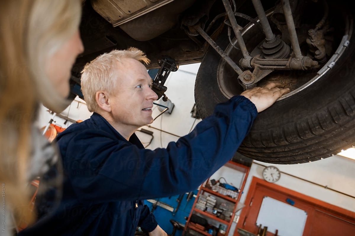 Mechanic Explaining Tire Problems To Customer In Garage