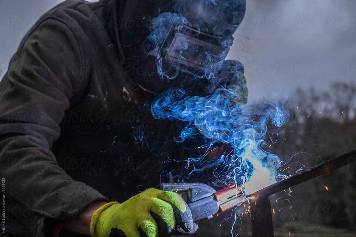 man welding, blue smoke