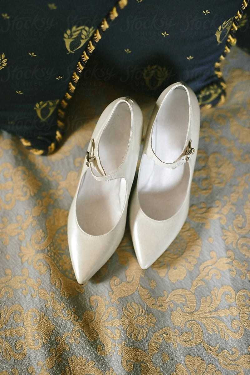 classic white wedding shoes on a royal Italian bed