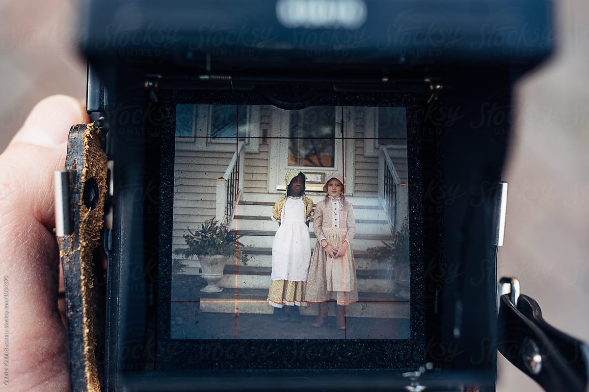 African American and Caucasian girls in old-fashioned dresses in a camera viewfinder