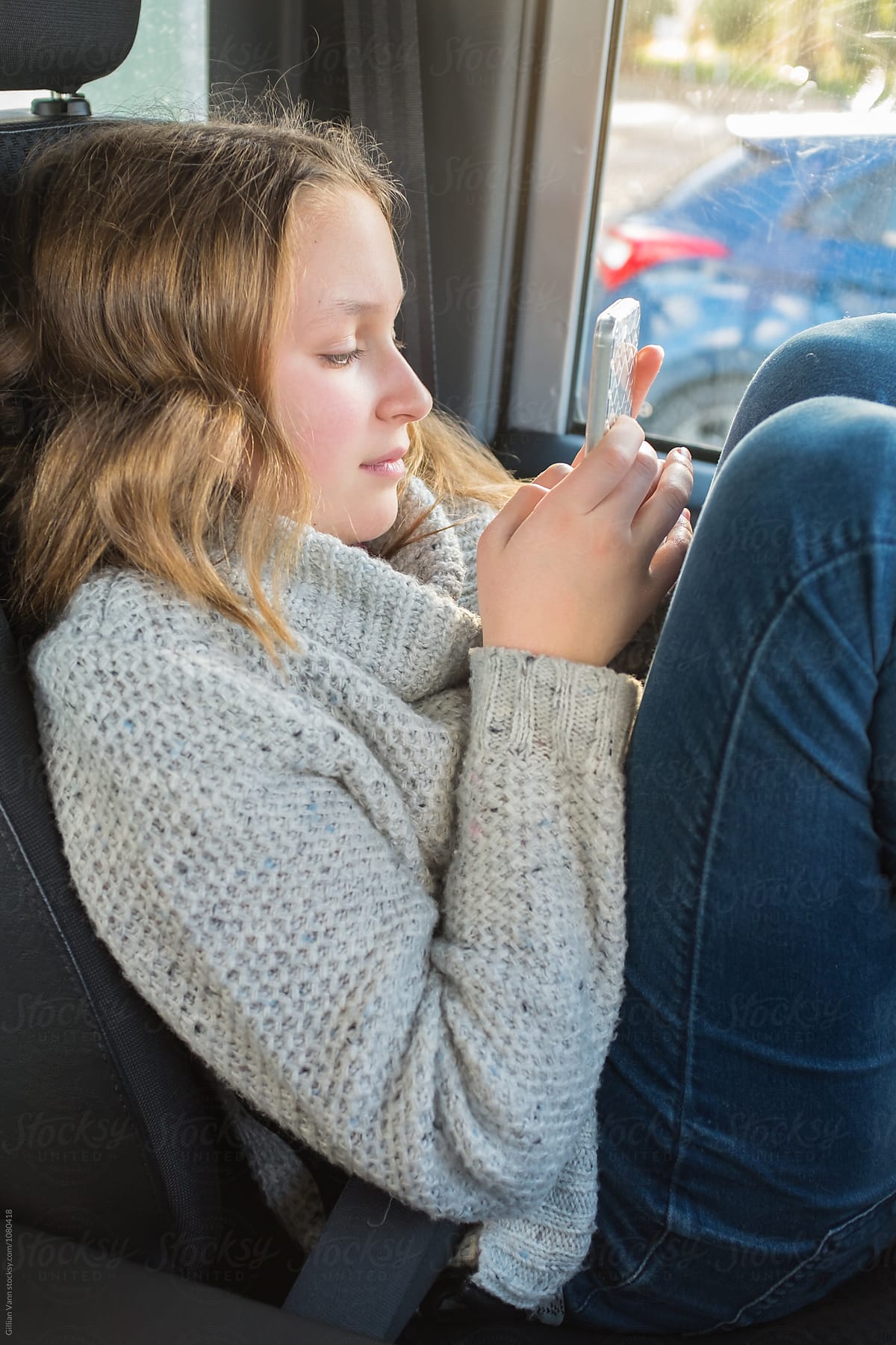 teen girl waiting in the car on her phone