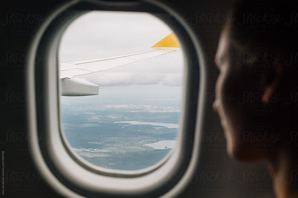 Woman looking through airplane window looking at wing