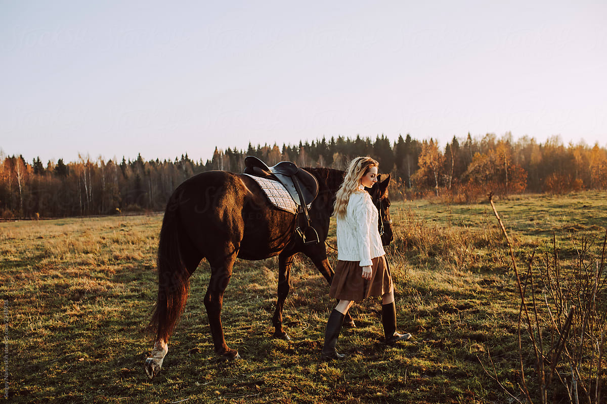 Elegant woman walking with horse in field