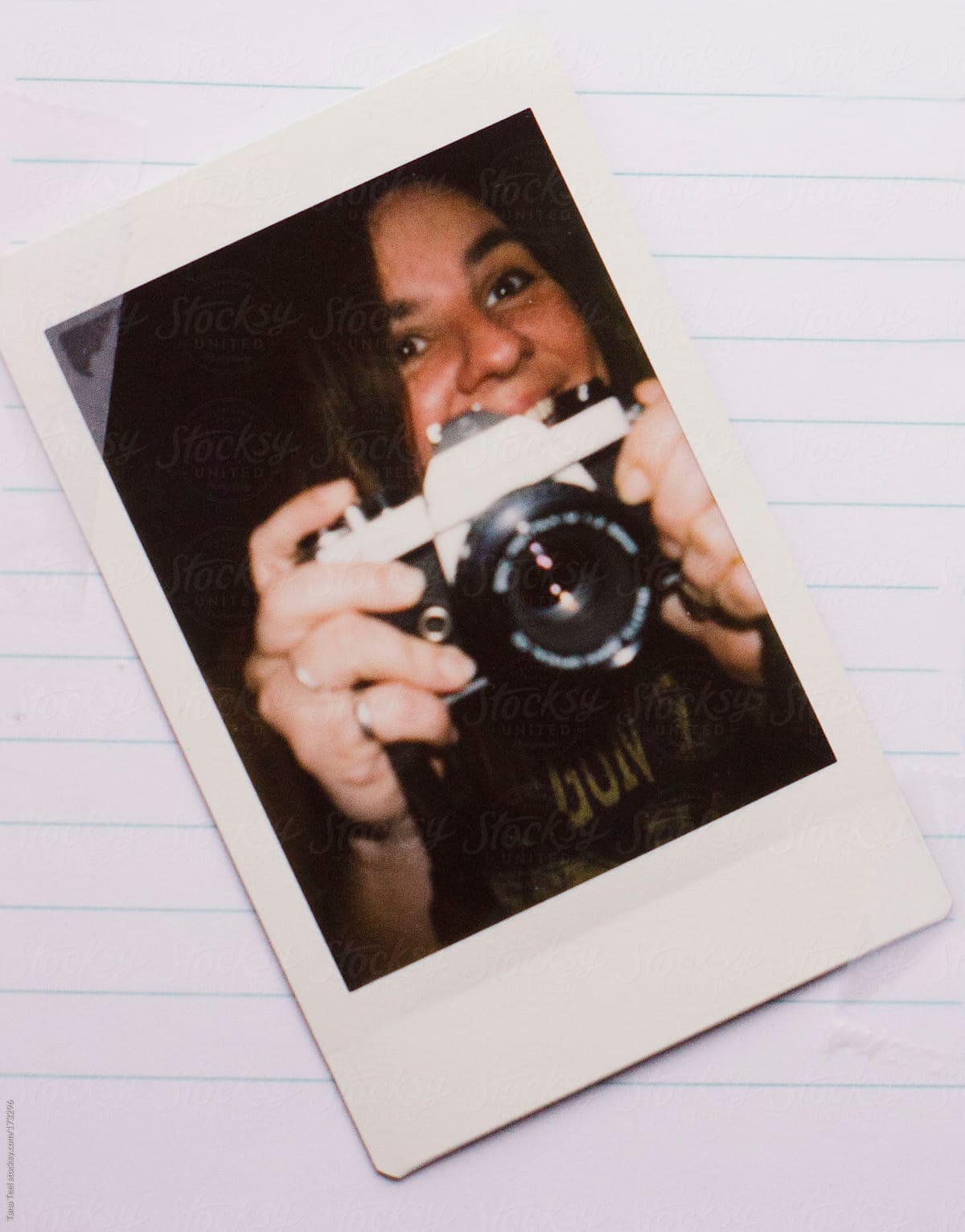 A mini polaroid of a smiling photographer placed on notebook paper