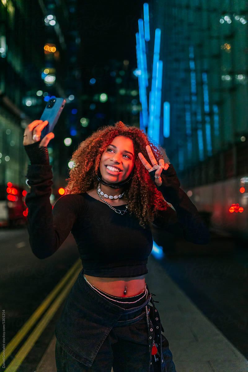 An afro girl takes a selfie in the city at night