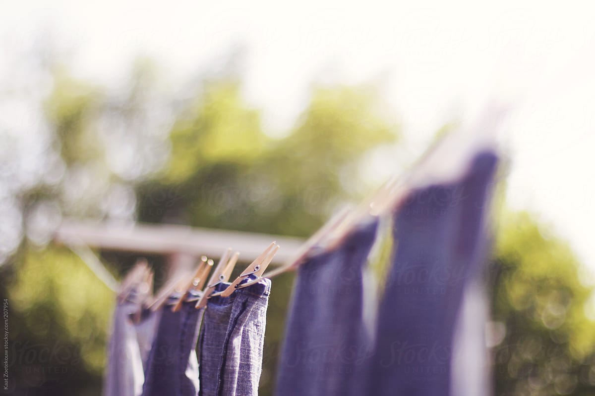 Wooden laundry pegs keep a firm grip on washed jeans drying outside on a line.