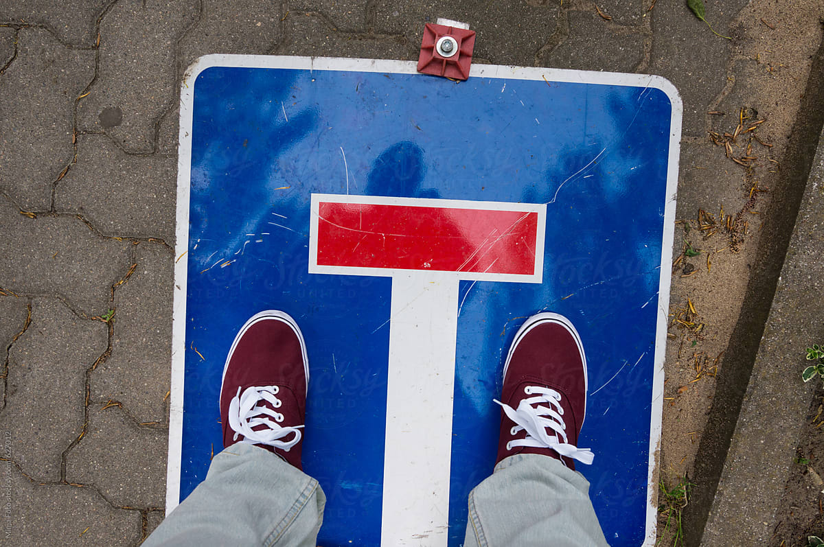Red sneakers on dead end traffic sign, footsie, personal perspective
