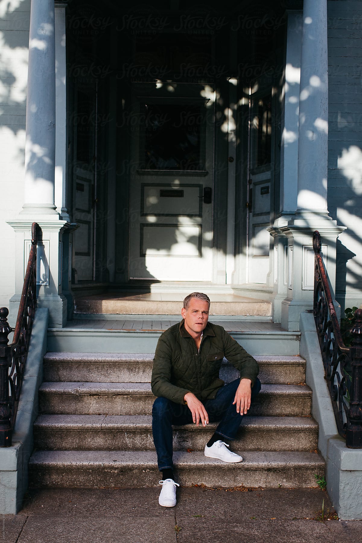 portrait of middle aged male smoking on stair case stoop entry apartment