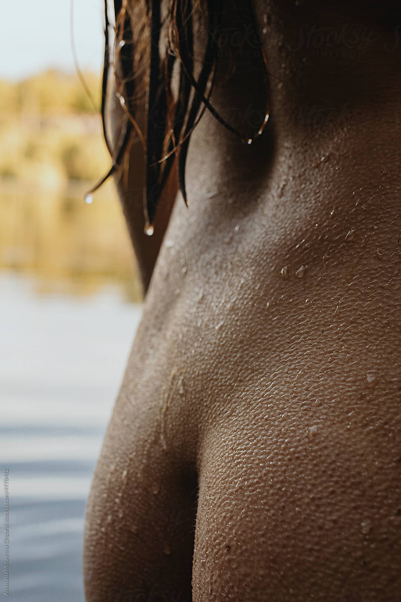 Nude tanned woman with wet hair and water drops on skin
