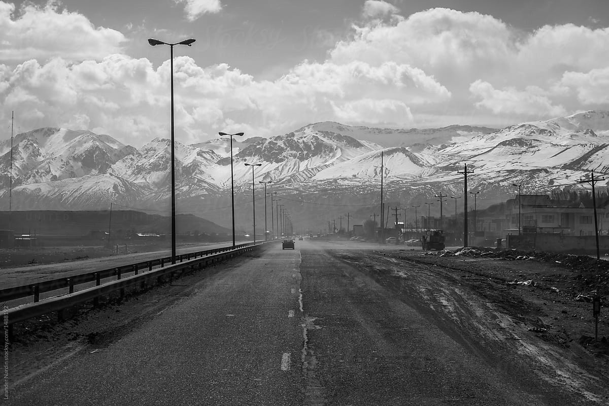 bad roads through dirty village leading to big snowcovered mountains - black and white