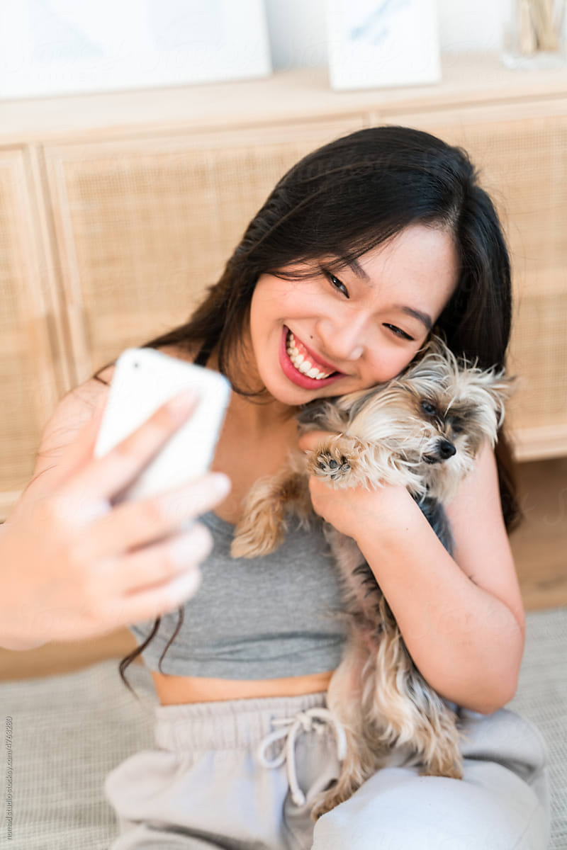 Woman taking selfies with her dog at home.