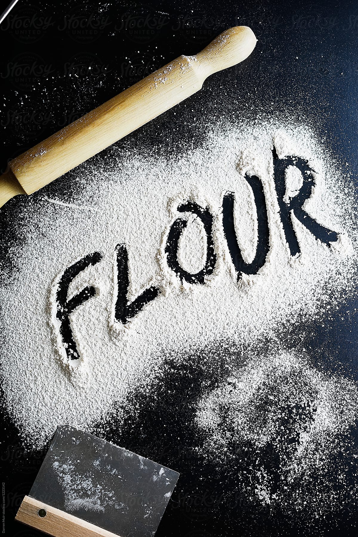 The word \'flour\' written with flour on a dark background.