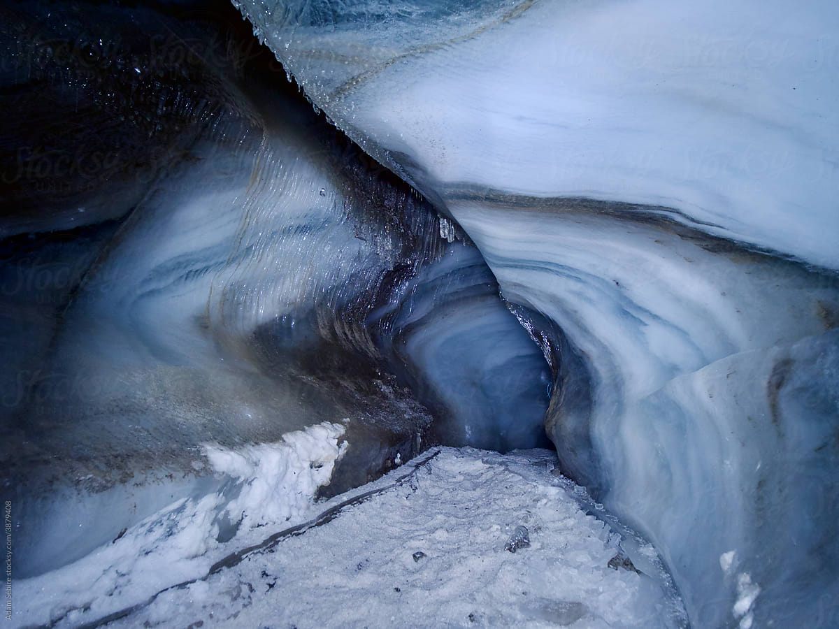 Glacier ice cave, Svalbard - tunnel with walking path leading beneath glacial surface