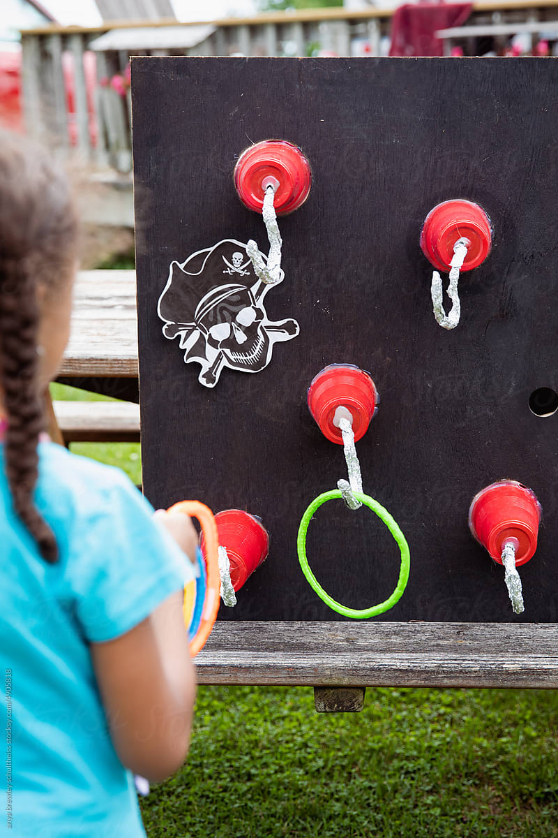Child throwing rings at a target filled with pirate hand hooks