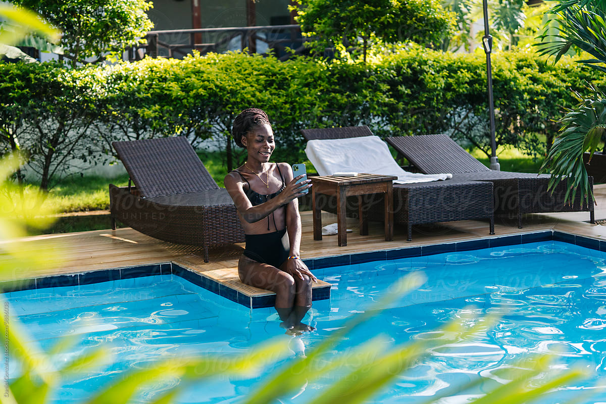 Black woman using mobile phone near pool at resort