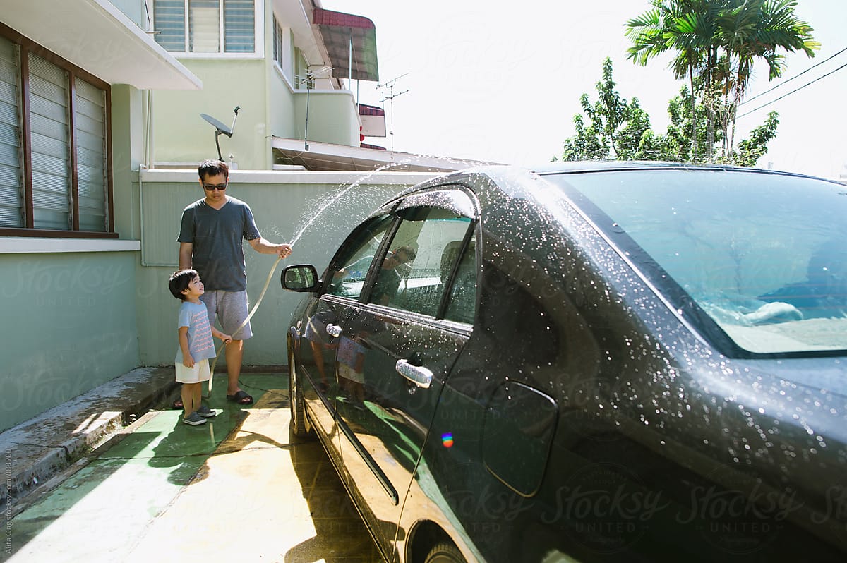 Dad and son washing car on sunny day