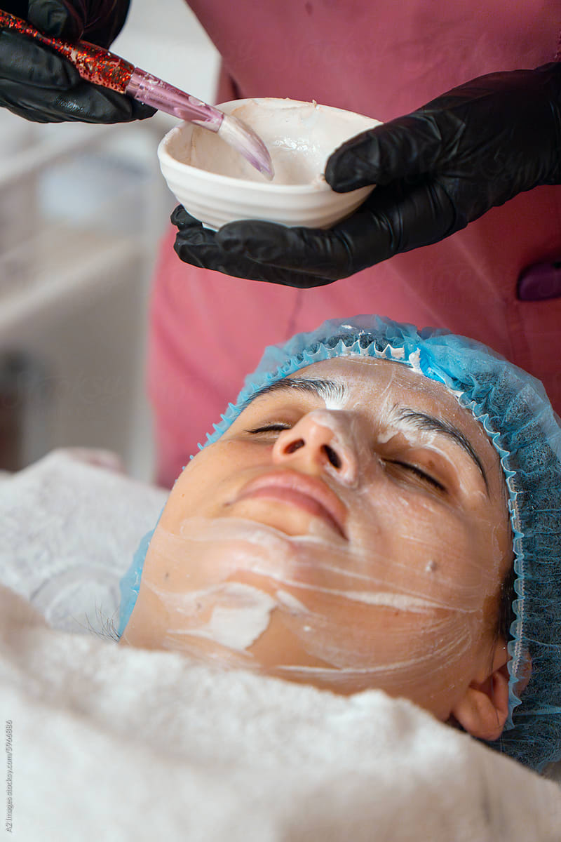 Spa therapist applying cream to her client\'s face